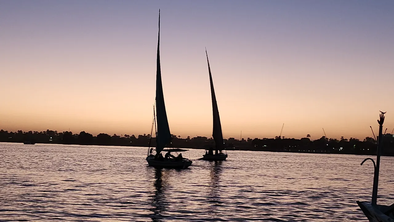 Two feluccas silhouetted on the Nile at sunset