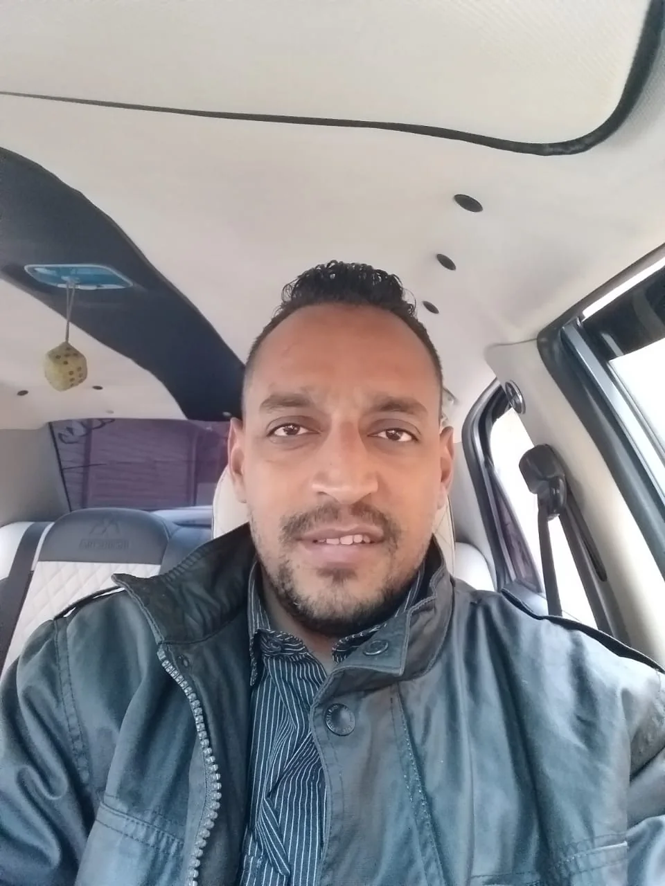Tito taking a selfie in the driver's seat of his taxi