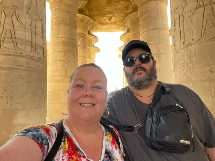 Two travellers taking a selfie among the carved columns of an ancient temple
